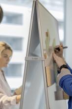 Person Writing on Whiteboard Others in the Background