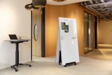 Laptop on high table, next to double-sided board with magnets in office environment