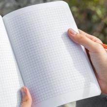 Leeres Notizbuch mit Karomuster, von Händen gehalten