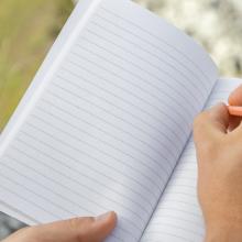 Geöffneter liniierter Notizblock, Hand schreibt