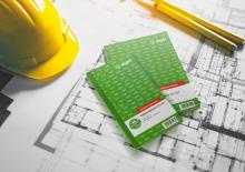 Gelber Bauhelm und grüne Blöcke mit Bauplänen