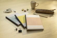 Notizbücher, Kaffeetasse, Stift und Büroklammern auf Holztisch