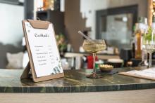 Cocktailkarte auf einer Theke, daneben ein Getränk in einem Glas mit Strohhalm