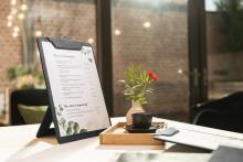 Speisekarte auf Tisch, Vase mit Blume