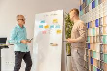 Two people discussing a sales campaign on a whiteboard with colorful sticky notes