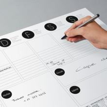 Hand schreibt auf Wochenplaner
