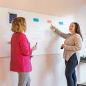 Zwei Kolleginnen tauschen sich an Whiteboard aus