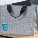 Hellgraue Desk Sharing Bag aus Filz mit blauem Logoaufdruck steht auf dem Schreibtisch