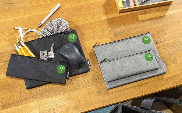 Unterschiedliche dunkel- und hellgraue Taschen-Organizer liegen auf einem Schreibtisch