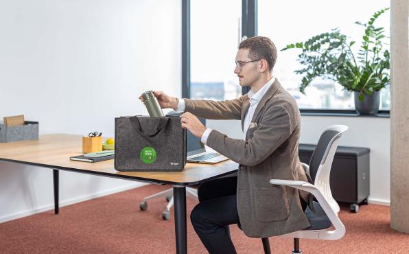 Dunkelgraue Tasche steht auf einem Schreibtisch