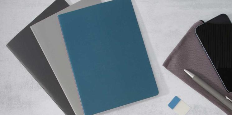 Stapel mit Linescape Notizheften in grau und blau liegen auf grauem Hintergrund