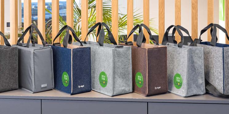 Desk Sharing Bags in unterschiedlichen Farben stehen auf einem Lowboard.