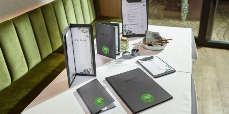 Auf einem schön gedeckten Tisch in einem Restaurant stehen und liegen Speisekarten.