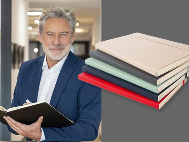 Ein Mann mit grauen Haaren hält ein schwarzes Business-Notizbuch in den Händen