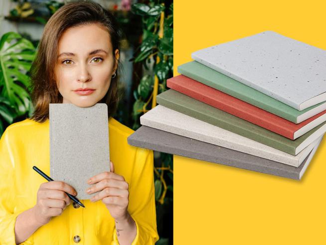 Eine dunkelhaarige Frau mit gelbem Pullover hält ein graues Notizbuch unters Kinn