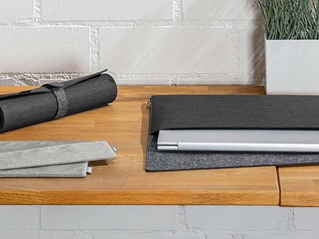 Laptop-Hüllen und Taschen für Büro Zubehör auf einer Holzplatte arrangiert.