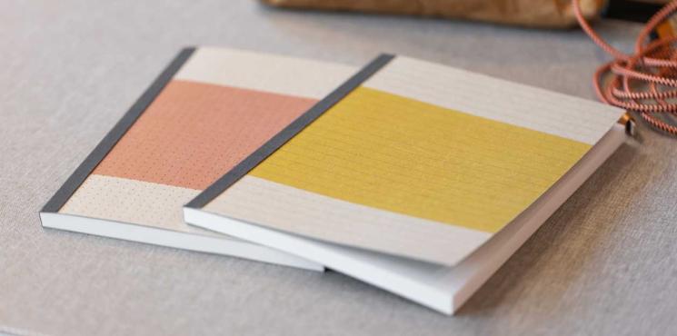 Zwei SIGEL Notizbücher in rot und gelb liegen auf Schreibtisch