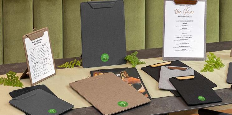 Auf einem Restauranttisch liegen unterschiedliche Klemmbretter mit Logoaufdruck