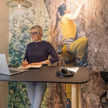 Frau steht an Schreibtisch und arbeitet