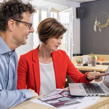 Zwei Menschen zeigen auf Laptop