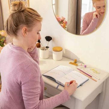 Frau reflektiert mit Notizbuch