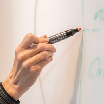 Hand mit Board-Marker schreibt an Whiteboard