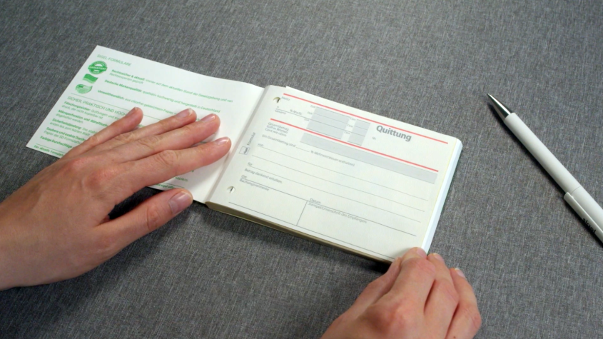 Zwei Hände schlagen Quittungsblock auf